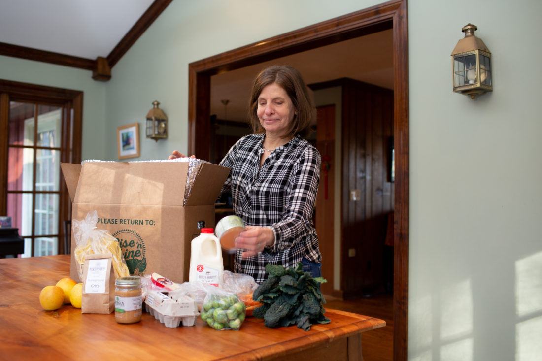 A woman takes items from a box surrounded by food